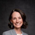 Reviews 1 Close up professional headshot of Sarah Jenkins, a luxury real estate team leader, wearing a grey blazer and smiling against a clean white background.
